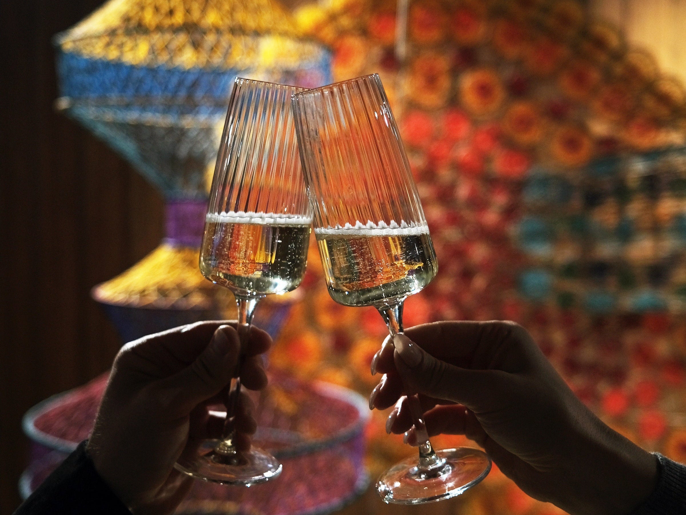 Two hands hold Exclusiva Flute glasses with wine cheering