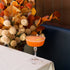 Cocktail in a glass with decorative flowers in the background