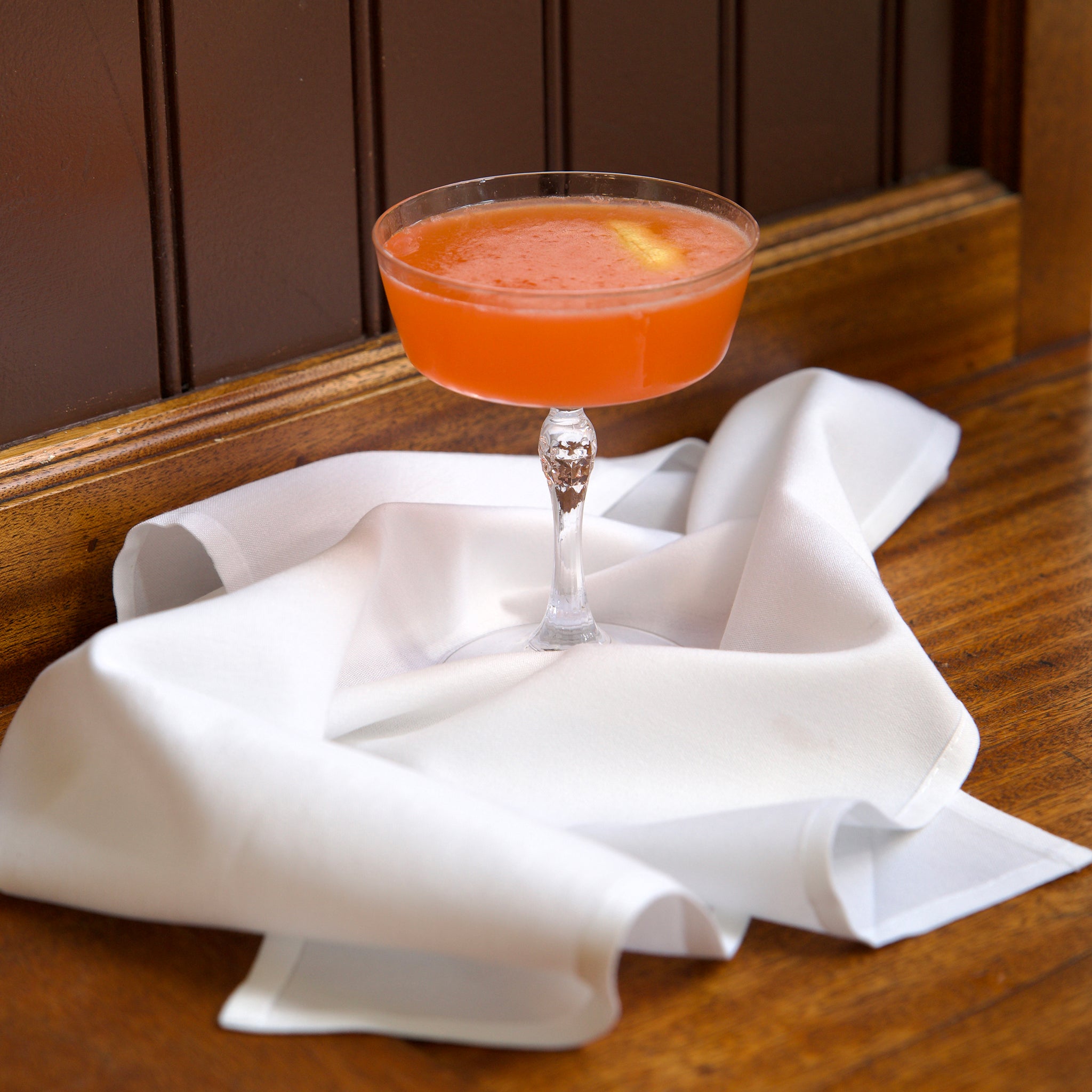 Cocktail in a glass on a white napkin with a wooden background