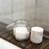 Glass jar with a marble lid on a wooden surface next to a marble container.