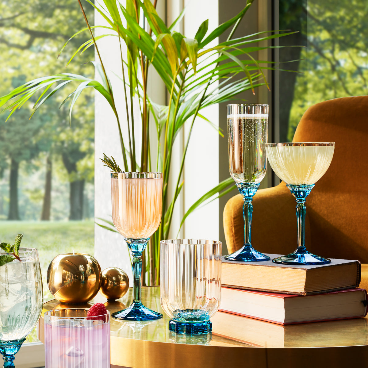 Florian glassware collection on a retro decorated table with books. Armchair, plants and a natural background. 