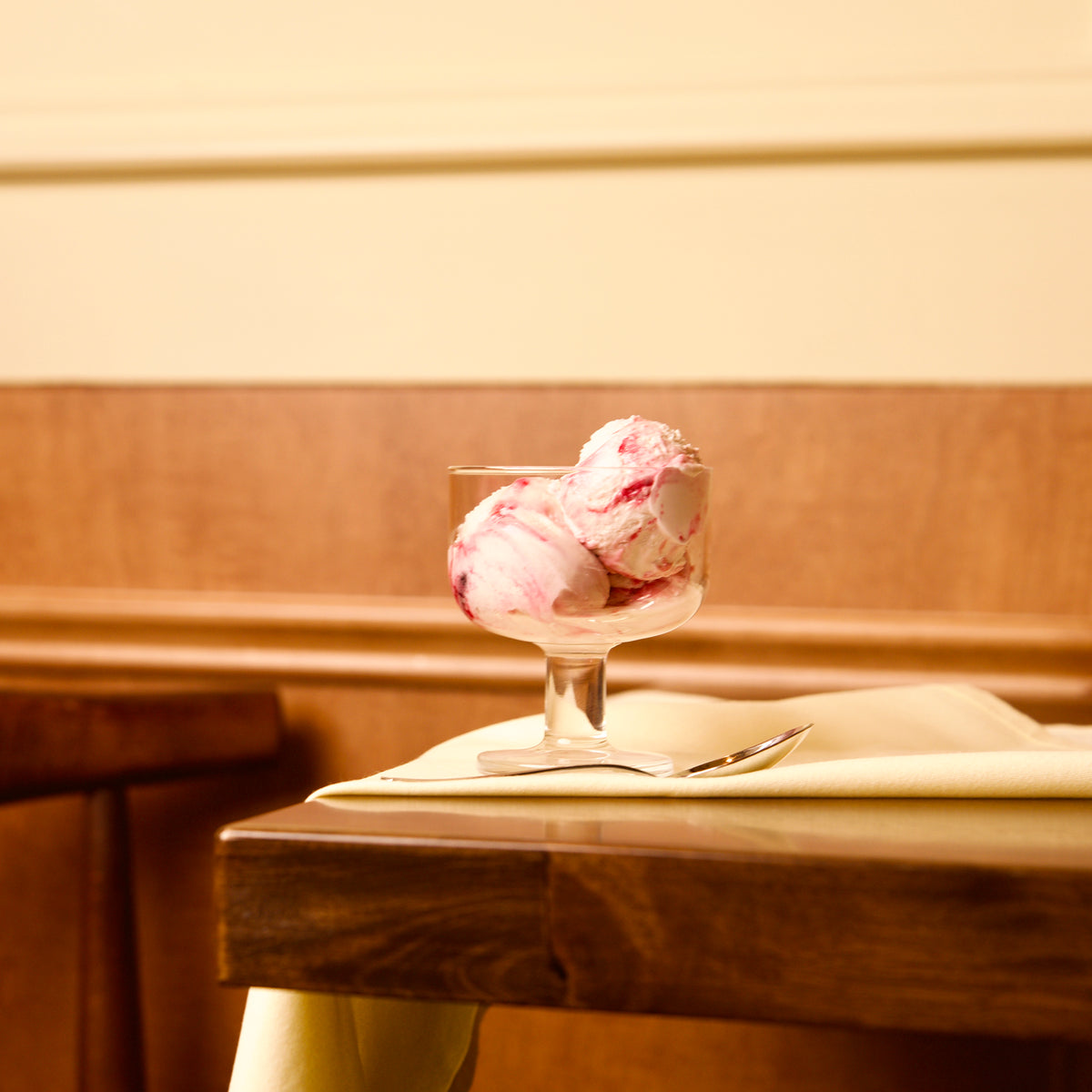 Hosteria dessert glass bowl with pink ice cream on a wooden surface