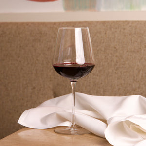 Glass of red wine on a wooden table with a white cloth, blurred background