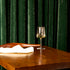 Planeo White wine glass filled with white wine standing on a wooden table with green curtain background