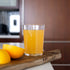 Glass of orange juice on a wooden cutting board with lemons in a kitchen setting