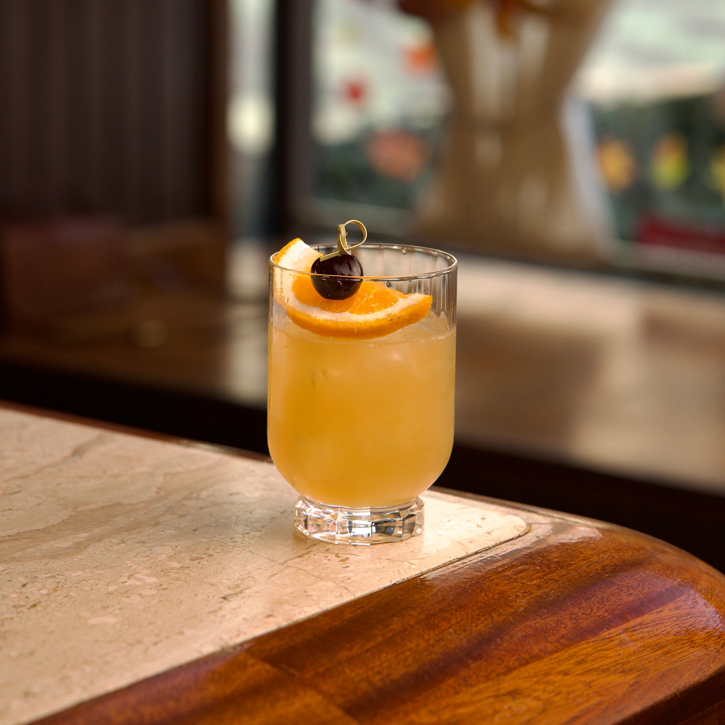 Cocktail with orange slice and cherry on a bar counter